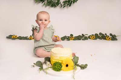 Girl in a green having a cake smash session with a yellow cake in Heywood